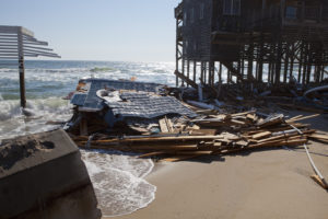 House destroyed off it's stilts with beach with the ocean washing on what was once a 3 story home