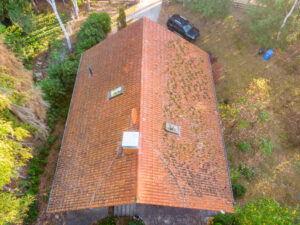 Aerial view of the red roof tile roof of a home, there is a black SUV in the foreground
